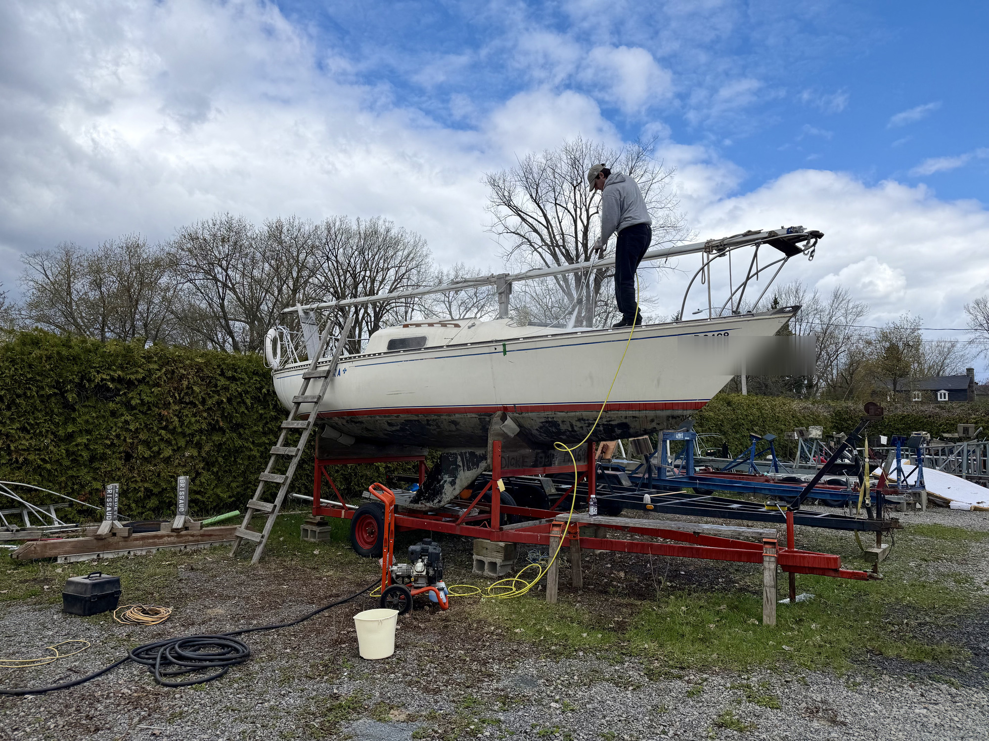Pressure washing the hull of a sailboat during seasonal cleaning.