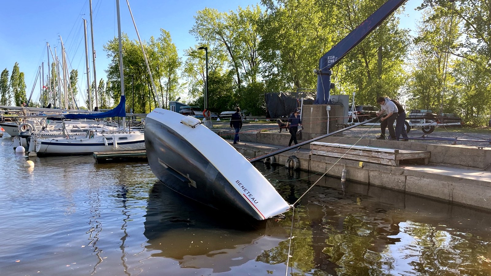 Sailboat tilted in the water during launch preparation and support.